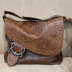 "Caramel brown Tooled Leather Crossbody Bag Handmade in Australia * Very strong bag. Will take heavy items.  * zipper closure under flap * choose silver or bronze hardware * Outside zipper pocket * Lining choices - See options * 3 inside slip pockets, all leather edged and riveted for easy access * Strap is made from strong double sided leather, double stitched * Features unique Celtic buckle SMALL SIZE bag Size: 28 cm wide at the bottom, by 24 cm high (11 inch x 9.5 inch) Depth at bottom: 5cm ( Brown Saddle Bag With Metal Hardware, Brown Saddle Bag With Metal Hardware Satchel, Brown Saddle Bag With Metal Hardware For Travel, Brown Saddle Bag With Brass Hardware, Brown Saddle Shoulder Bag, Brown Saddle Shoulder Bag With Metal Hardware, Brown Saddle Shoulder Bag With Brass Hardware, Vintage Brown Hobo Bag With Leather Backing, Brown Leather Saddle Bag Crossbody