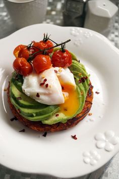 an avocado sandwich with tomatoes and sour cream on top is sitting on a white plate