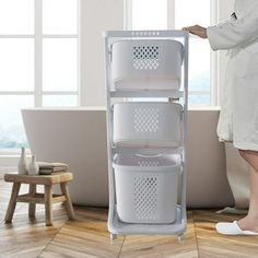 a woman standing next to a bath tub with three baskets on the bottom and one in the middle