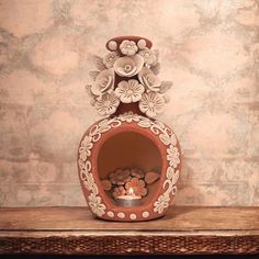 a decorative vase with flowers and candles in it on a shelf next to a wall