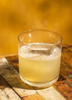 a glass filled with liquid sitting on top of a wooden table