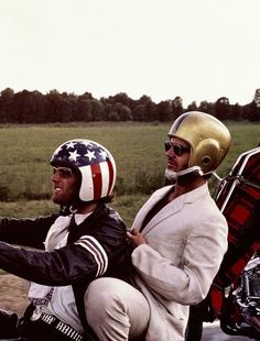 two men riding on the back of a motorcycle with an american flag painted on it