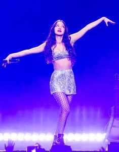 a woman in fishnet tights on stage with her arms out and hands outstretched