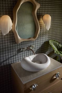 a bathroom sink sitting under a mirror next to a wall mounted faucet with lights on it