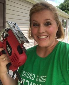 a woman in a green shirt holding a red and black tool