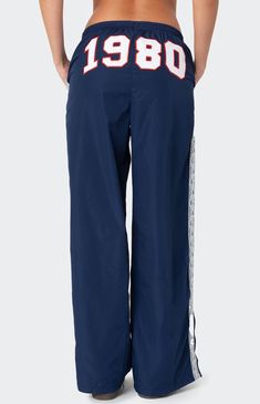 These Edikted 1980 Nylon Track Pants offer both style and comfort, making them perfect for a sporty yet fashionable look. They're ideal for any activity, ensuring you feel comfortable and confident throughout your entire day. Track pantsLace stripe detailingSlitted hemAdjustable waist tieEmbroidered graphic textPolyesterModel wears size SModel height is 5'8Item care: Machine wash at maximum 30C, wash with similar colors, do not bleach, do not tumble dry, iron at a maximum of 110C, do not dry clean. Edikted Womens 1980 Nylon Track Pants - Blue size XS Sweatpants With Words On Back, Extra Long Pants, Sporty Fits, White Track Pants, Aesthetic Pants, Cool Sweatpants, Vintage Sweatpants, Nylon Track Pants, Graphic Sweatpants