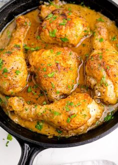 chicken thighs in a skillet with gravy and parsley