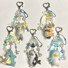 three keychains with charms attached to them on a white surface, one has a penguin and the other is a penguin