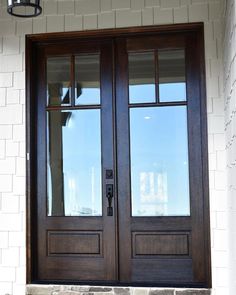 two brown double doors sitting next to each other on a brick wall and stone steps