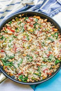 a skillet filled with beans, spinach and parmesan cheese on top