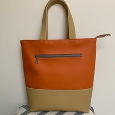 an orange and tan purse sitting on top of a striped chair next to a white wall