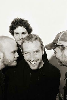 a group of men standing next to each other in front of a white wall smiling