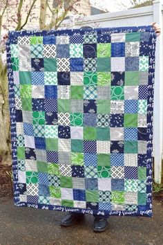 a person standing next to a large blue and green quilt