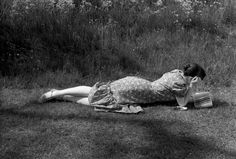 a woman laying on the ground with her head in her hands while reading a book