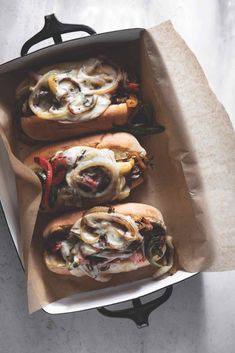 two hot dogs in buns with toppings sitting on top of a paper wrapper