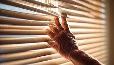 a person's hand is reaching for the blinds