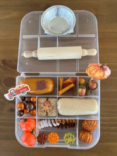 a plastic container filled with lots of different types of food and condiments on top of a wooden table