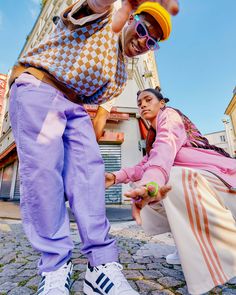 two people are standing on the street and one person is holding something in his hand