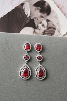 Vintage style  zircon  earrings  Colour: rhodium(silver tone) /clear/red Measurements: approx 5.1 cm x 16 mm  including studs(medium size not very long).  Materials:  rhodium over brass components, zircon crystals . Stud earrings. Great for wedding or other celebration. Same style with clear crystals: https://www.etsy.com/uk/listing/642610631/bridal-earringsart-deco-earrings-crystal?ref=listing-shop-header-0 MORE SAME STYLE: https://www.etsy.com/uk/shop/BridalArtDeco?ref=listing-shop-header-item Red Sterling Silver Earrings For Wedding, Red Dangle Chandelier Earrings For Anniversary, Red Chandelier Drop Earrings For Wedding, Red Teardrop Chandelier Earrings For Wedding, Red Dangle Bridal Earrings For Anniversary, Red Round Bridal Earrings For Anniversary, Formal Red Round Bridal Earrings, Red Chandelier Earrings For Anniversary, Red Teardrop Crystal Earrings For Wedding