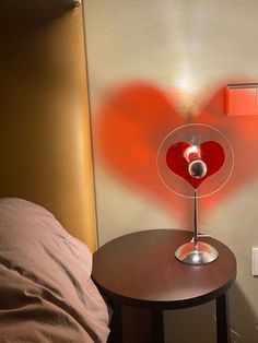 a lamp that is sitting on top of a table next to a bed with a heart drawn on it