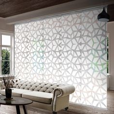 a living room with a couch, table and large glass window that has geometric designs on it