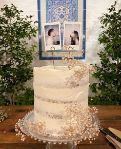 a white wedding cake with two pictures on the top and one is frosted in icing