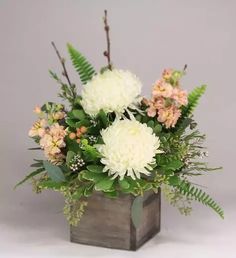 a wooden vase filled with white and pink flowers on top of a gray tablecloth