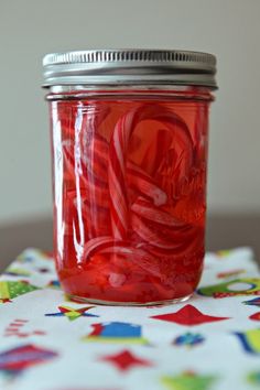 a glass jar filled with red liquid sitting on top of a colorful tablecloth covered table