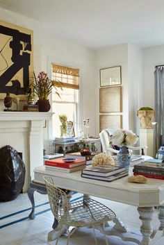 a living room filled with furniture and a fire place next to a white table covered in books