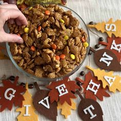 a bowl filled with candy cornflakes on top of a table next to fall decorations