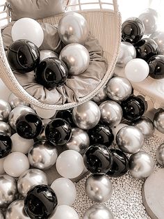 a basket filled with lots of black and white balls next to a pile of silver and white balloons