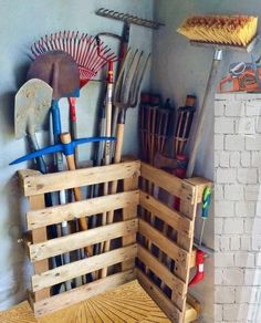 a bunch of gardening tools are in a wooden crate on the floor next to a wall