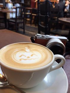 a cappuccino on a saucer with a camera in the background