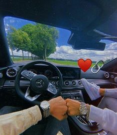 two people holding hands while driving in a car