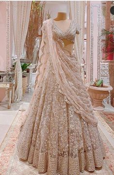 a wedding dress on display in a room with white curtains and pink carpeted flooring