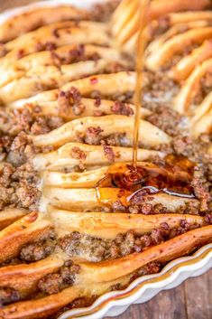 someone is pouring syrup on some food in a pie pan with french fries and other toppings