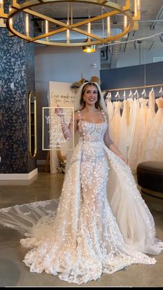 a woman in a wedding dress standing next to a rack of gowns at a bridal shop