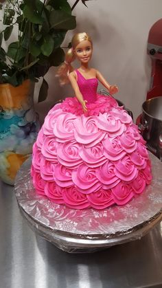 a barbie doll sitting on top of a cake