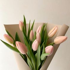 a bouquet of pink tulips sitting on top of a white paper wrapped vase