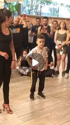 a woman standing next to a little boy on top of a dance floor