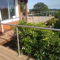 a balcony with railings and bushes on the side of it, next to a building