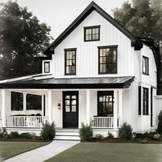 a white house with black trim on the front and side windows, along with two porches