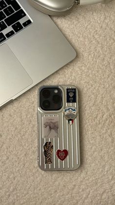 an iphone case with stickers on it sitting next to a laptop computer and mouse