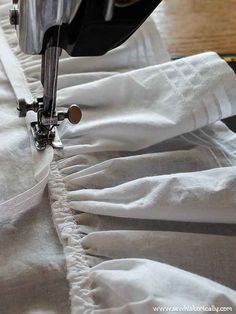 the sewing machine is working on the white linens that are being sewn together