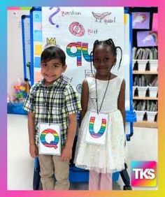 two young children standing next to each other in front of a sign with the letter u on it