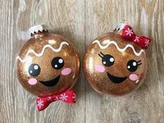 two christmas ornaments with faces on them sitting on a wooden floor next to each other