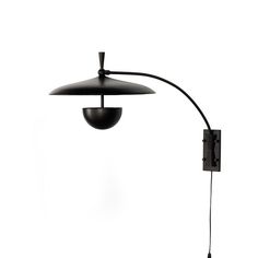 a black lamp on a white wall with a light attached to the back of it