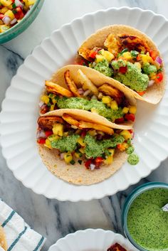 two tacos with guacamole, corn and salsa on them sitting on a white plate