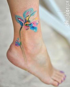 a woman's foot with a colorful flower tattoo on the side of her leg