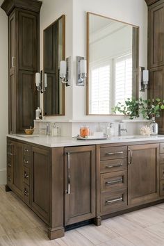 a large bathroom with two sinks, mirrors and cabinets in it's center area